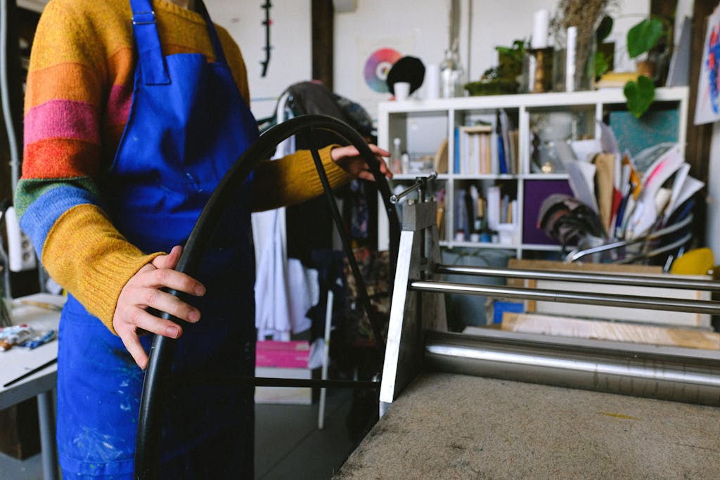 Professional craftswoman working on printing machine in workshop